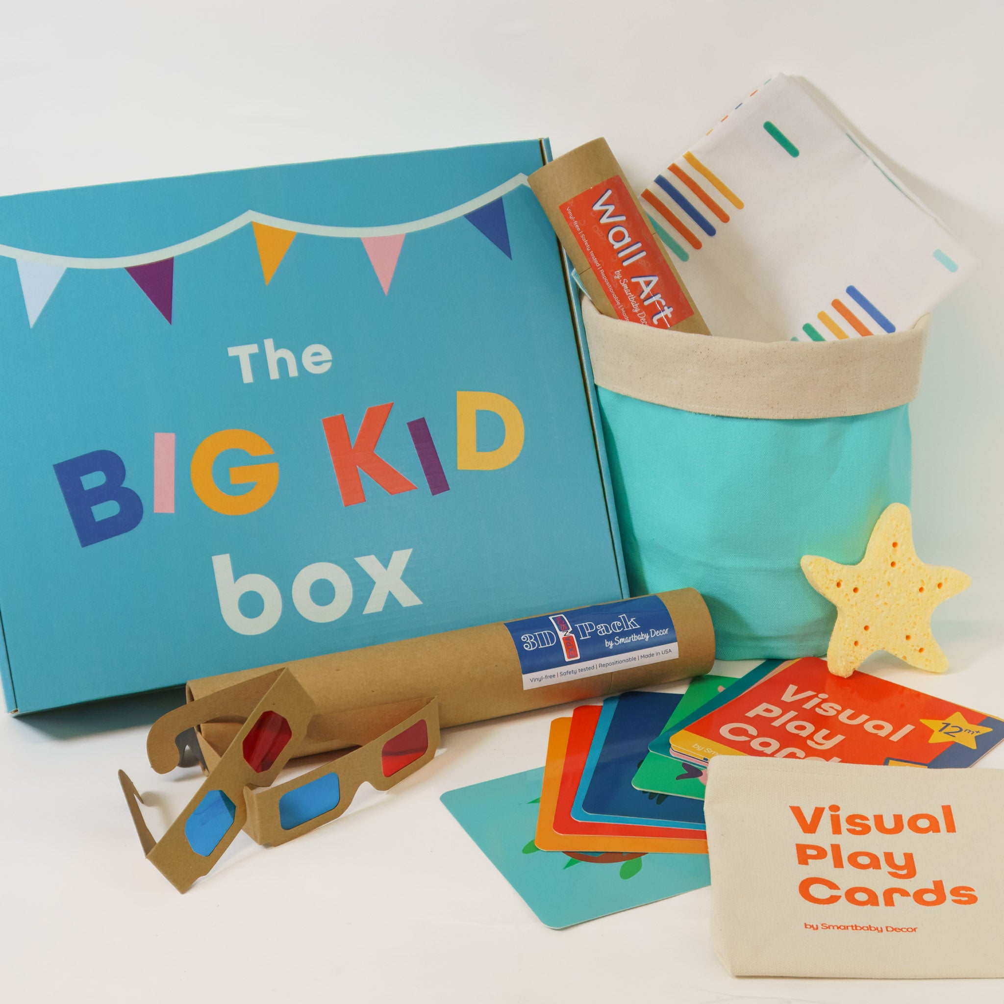 Contents of big kid gift box displayed including wall art, 3D glasses, visual play cards, bath sponge, storage basket and throw pillow cover