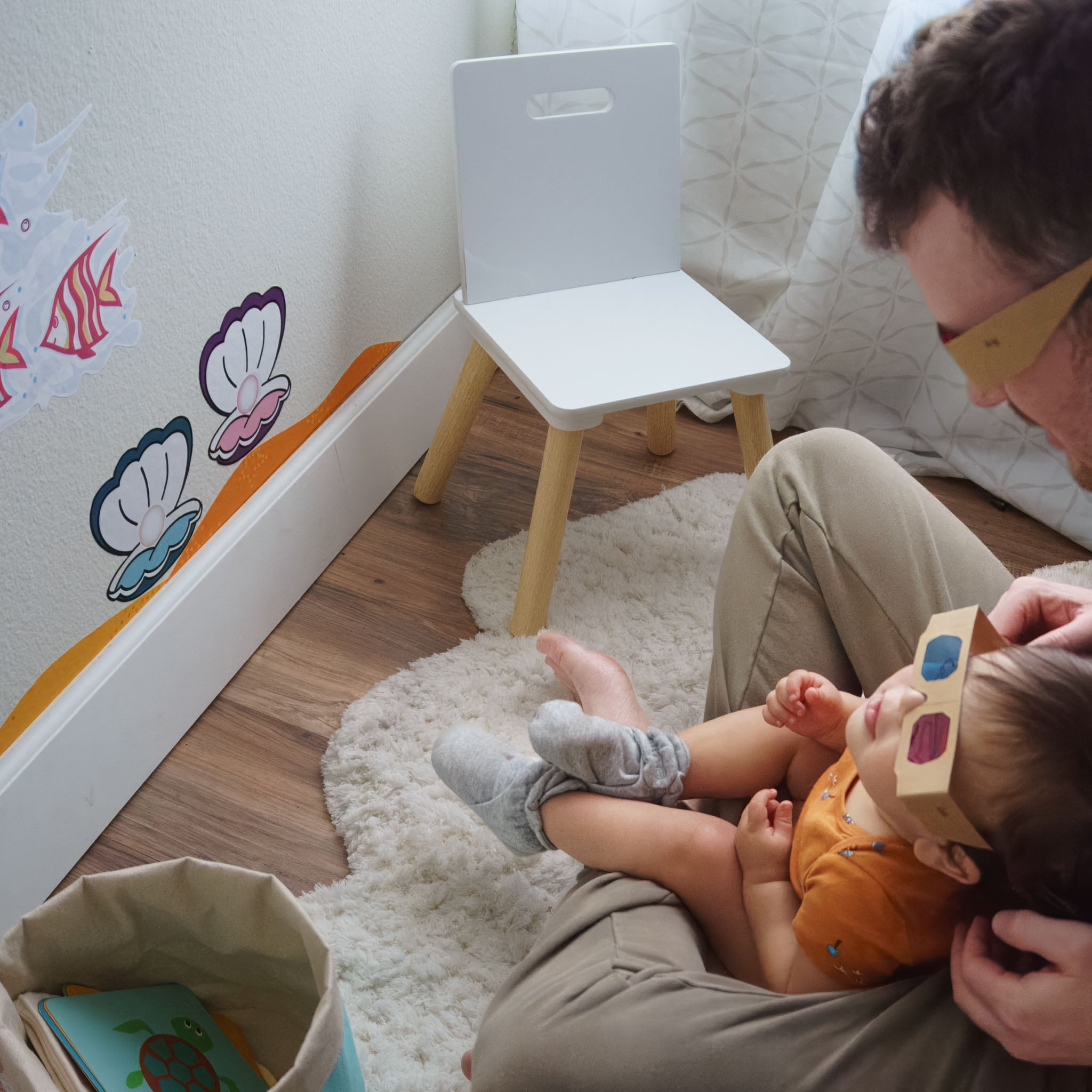 Toddler boy sitting in dad's lap, both wearing 3D glasses viewing 3D wall art