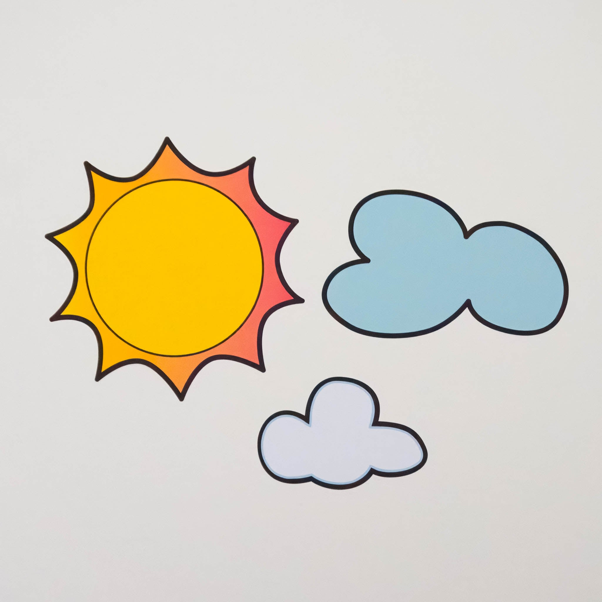A white background with sun and clouds wall stickers on it.