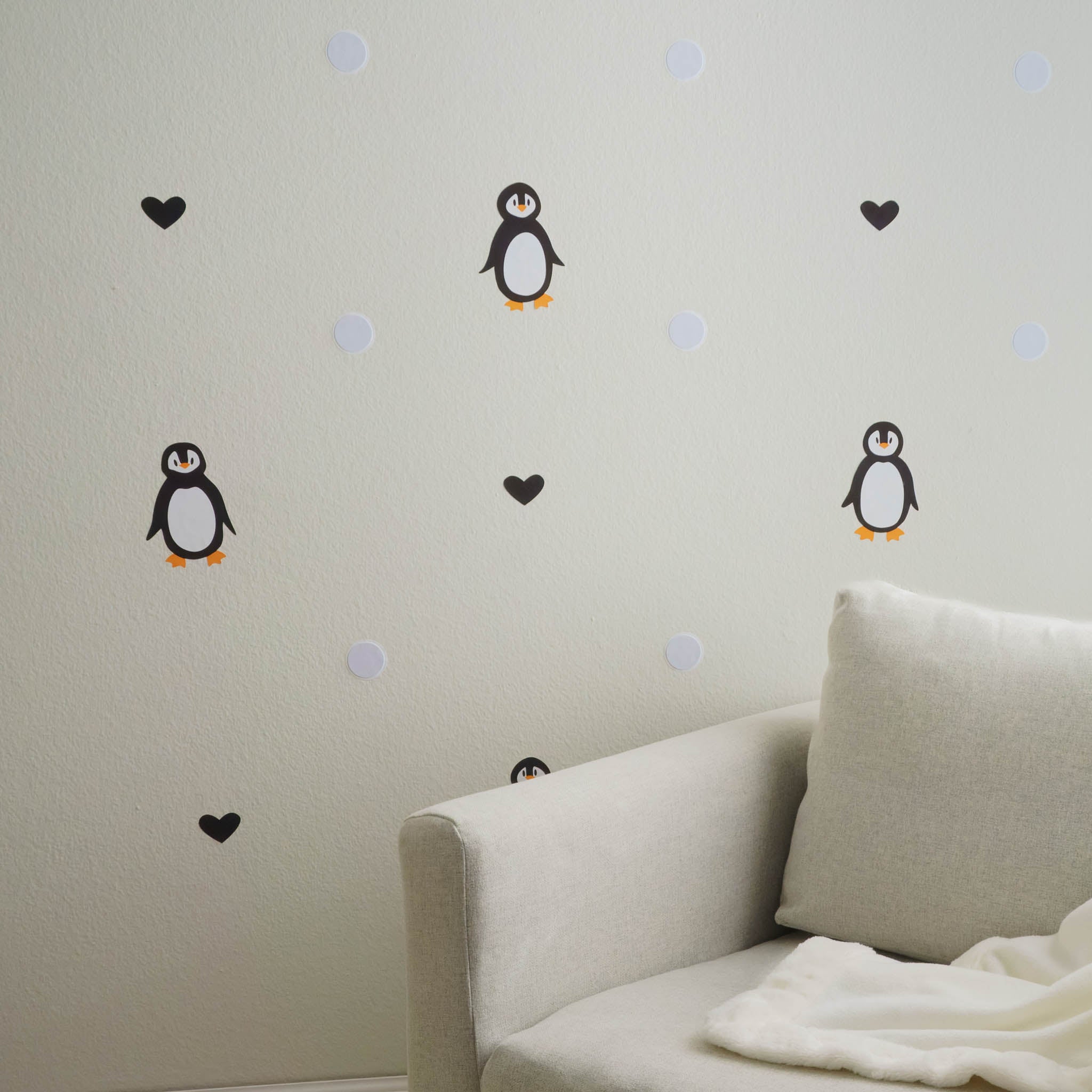 Alternating penguin, black heart and snowball wall decals on wall next to couch and blanket