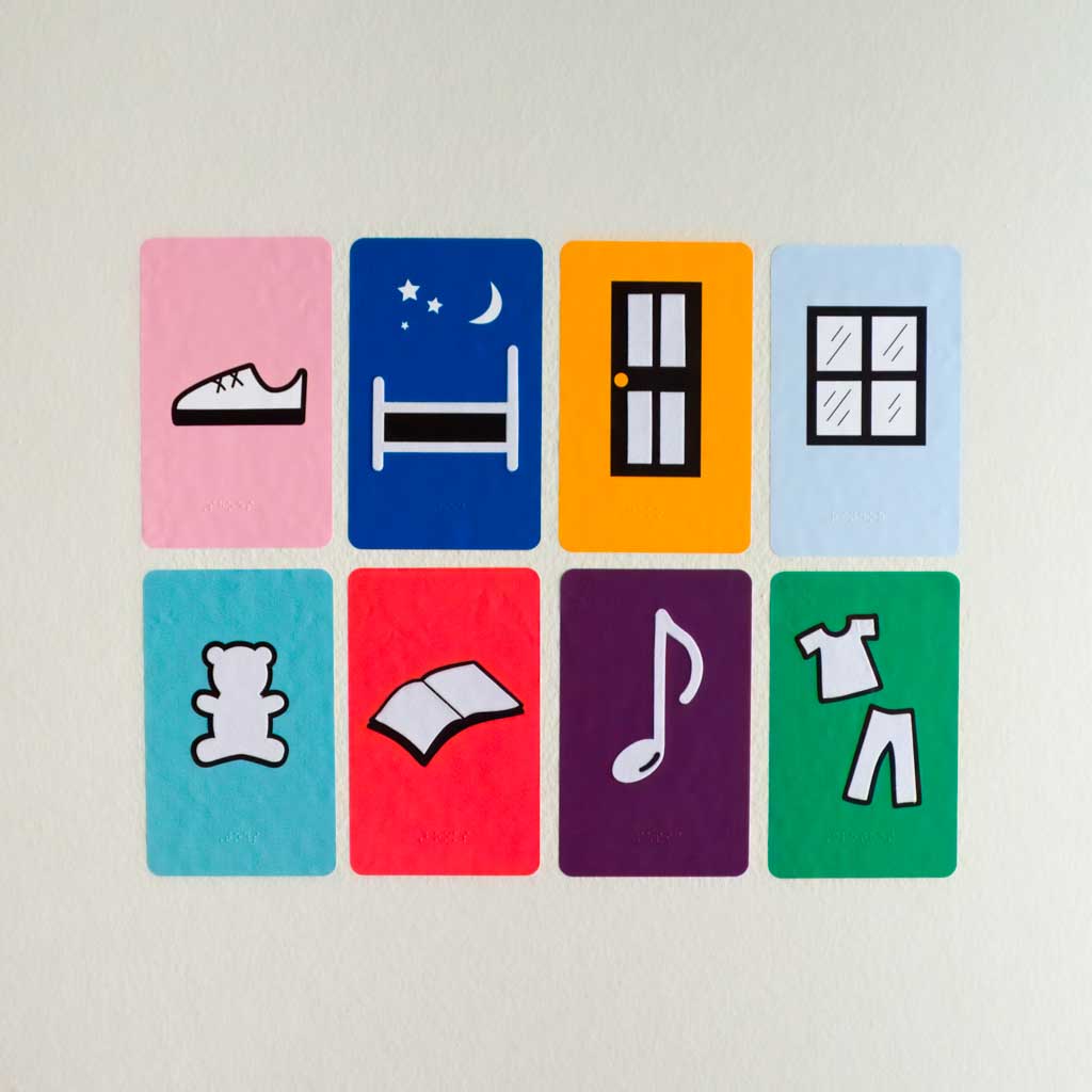 8 different high contrast shapes on different colored backgrounds including a shoe, bed, door, window, teddy bear, book, music note, and clothes