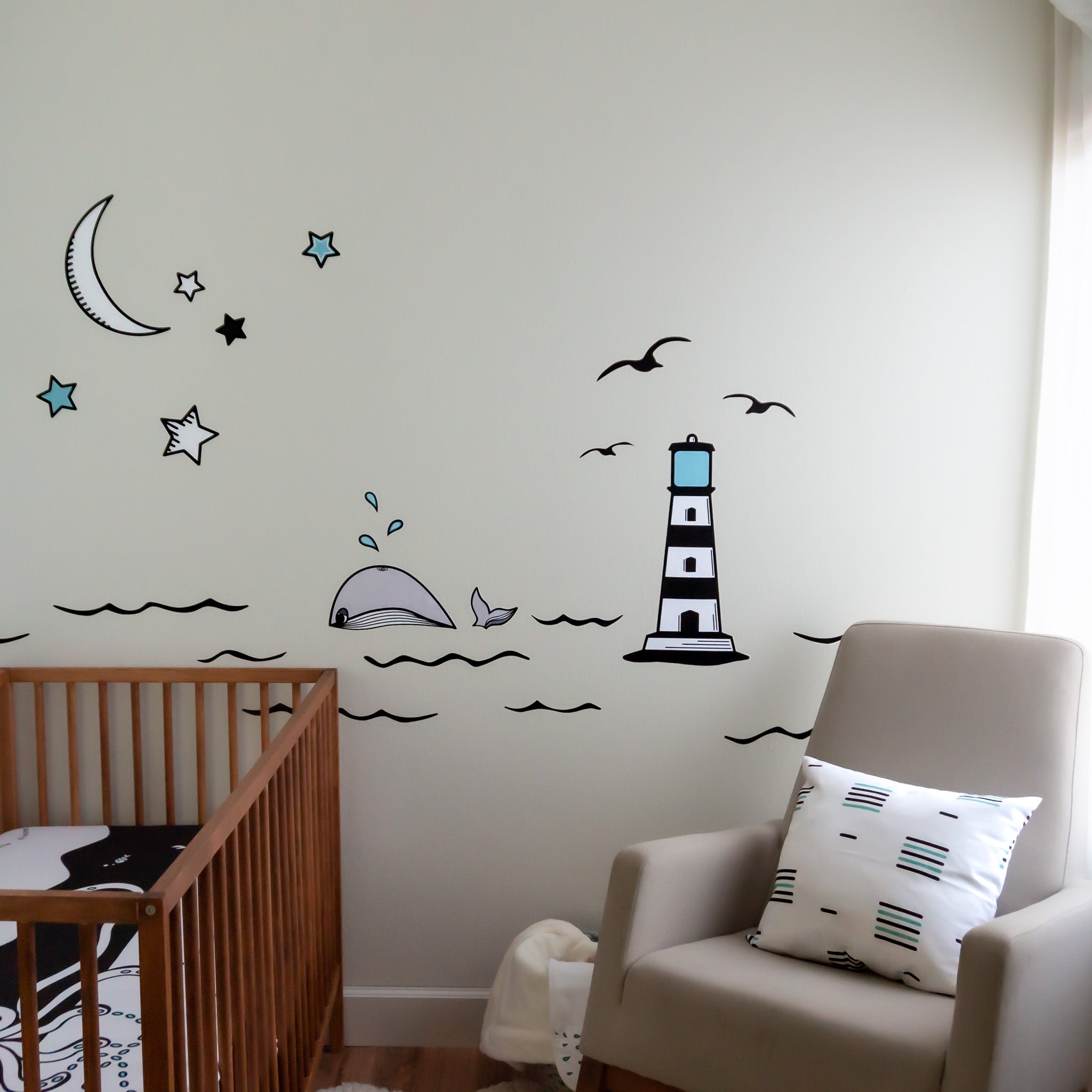A nursery with a wall mural of an ocean theme, a rocking chair on the right and a wooden crib on the left.